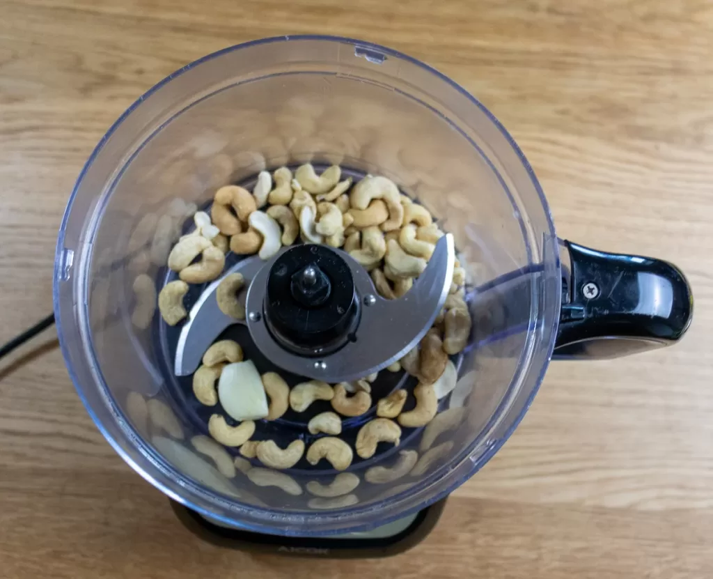Top down shot into food processor with garlic and cashews