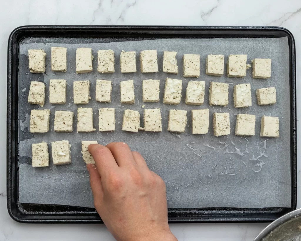 Adding tofu to oiled tray 2