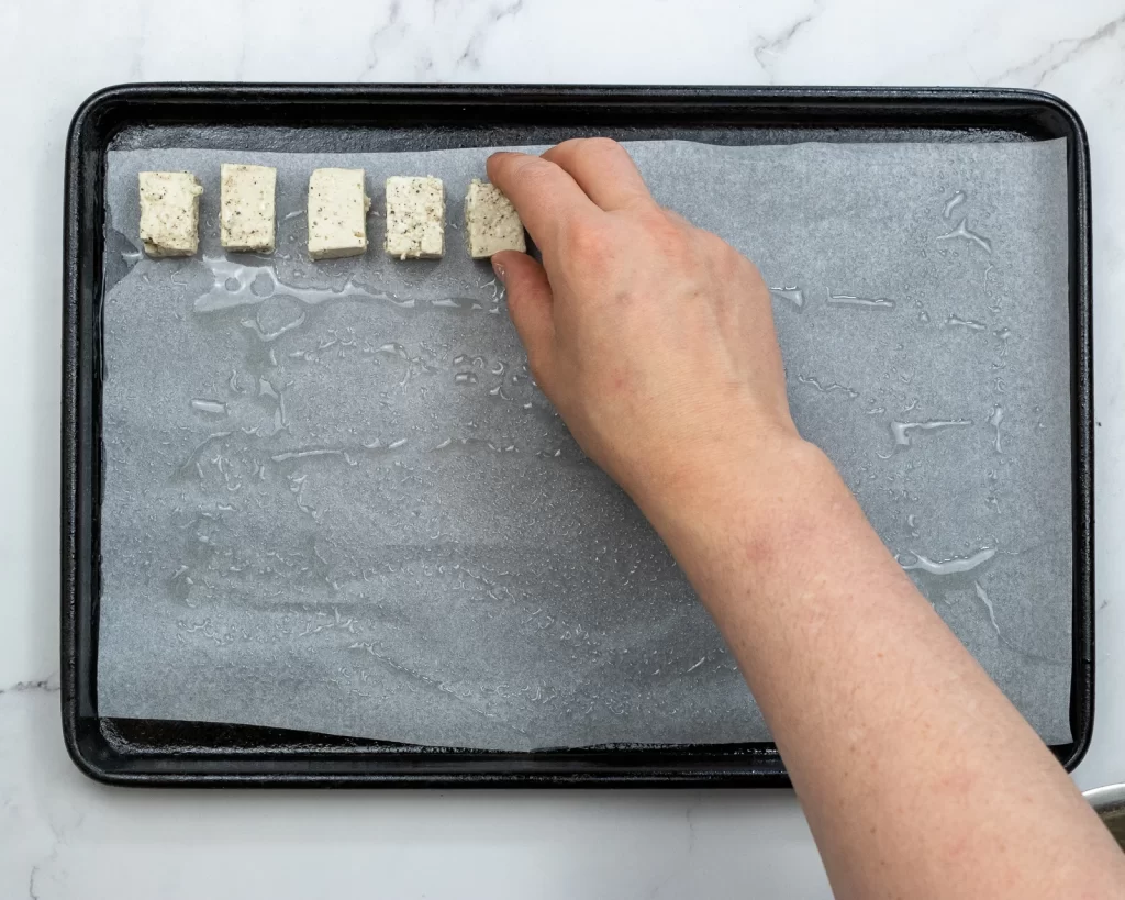 Adding tofu to oiled tray