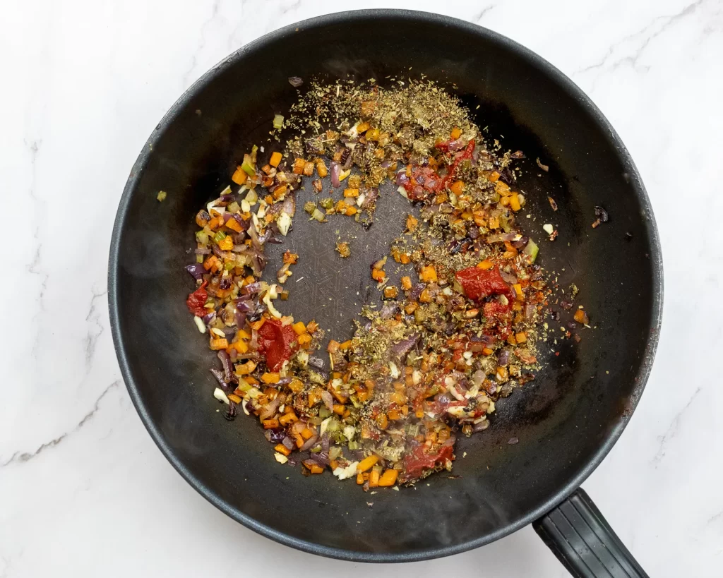 Adding herbs and tomato paste